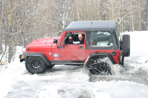 2003 Jeep TJ - A red 2003 Jeep TJ navigates through a partially frozen body of water during winter.