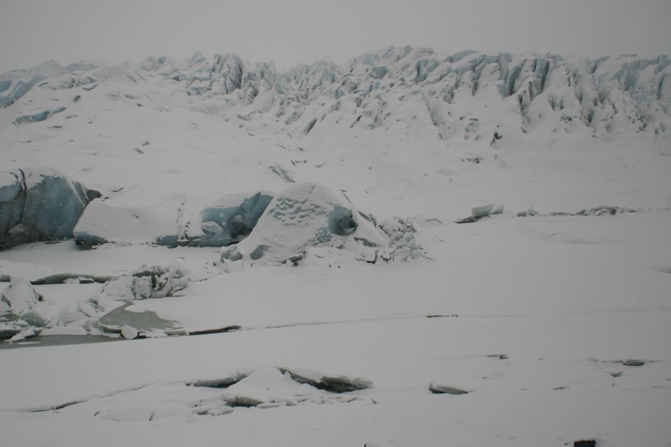 snowy glacier with ice formations and a frozen body of water