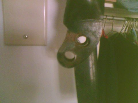 1985 Ford F-150 - A close-up of a rusty metal bracket with two holes, mounted on a dark pole.