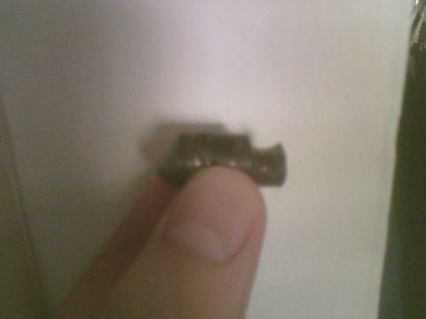 1985 Ford F-150 - A small metal component is held between a finger and thumb against a plain background.