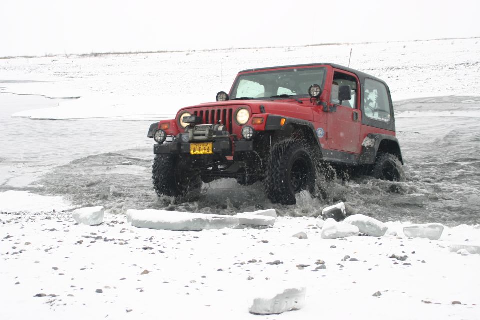 Red 2003 Jeep TJ driving through icy water