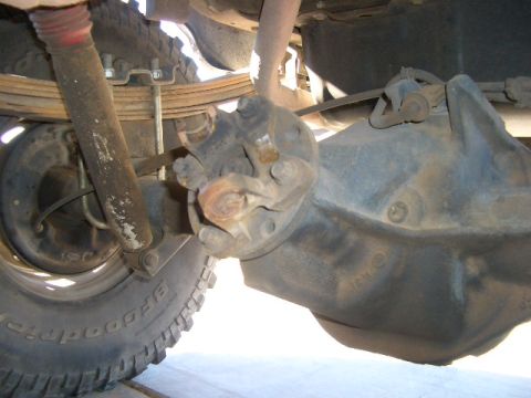 1990 Ford Bronco - Close-up view of the rear axle and suspension system, including leaf springs and a shock absorber.
