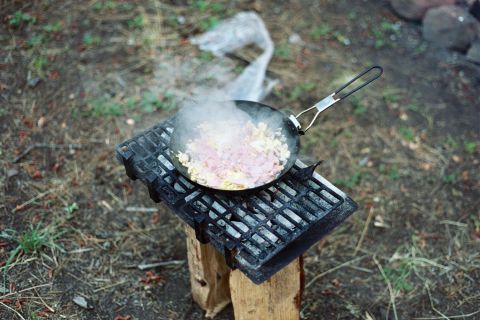 1979 Ford Bronco - A meal is being prepared outdoors on a makeshift grill setup.