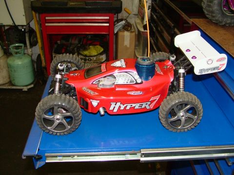 1994 Ford Bronco - This red remote control car, labeled 'HYPER 7', sits on a blue surface with a visible engine and spoiler.