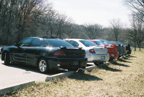 2004 Dodge SRT-4 - A line of sedans, including a black Grand Am and a silver Neon, are parked in a lot.