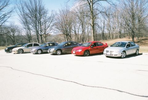 2004 Dodge SRT-4 - A group of Dodge Neons are lined up in a parking lot with trees in the background.