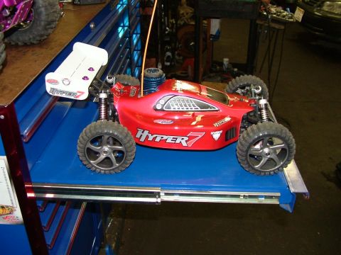 1994 Ford Bronco - A red remote control buggy with a white spoiler is displayed on a blue surface, with other vehicles in the background.