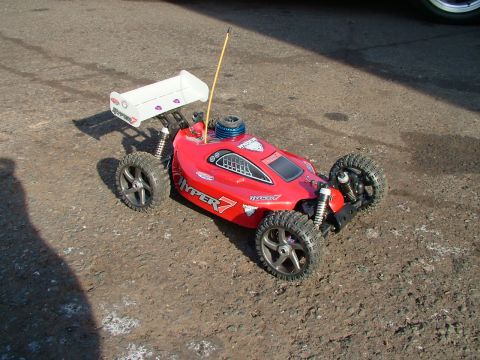 1994 Ford Bronco - A red remote control buggy, labeled 'HYPER 7', sits on a dirt surface with its white spoiler visible.