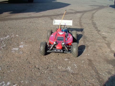1994 Ford Bronco - A red remote control buggy with a prominent spoiler sits on a rough surface, ready for action.