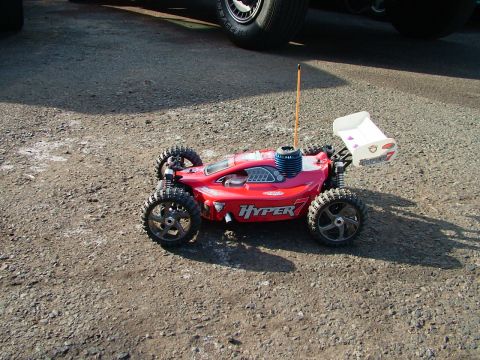 1994 Ford Bronco - A red remote control car with off-road tires sits on a gravel surface.
