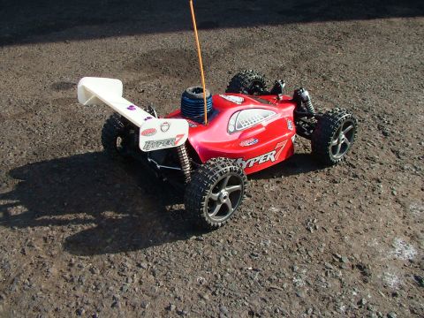 1994 Ford Bronco - A red remote control buggy with a white spoiler and 'HYPER 7' branding is parked on a dirt surface.