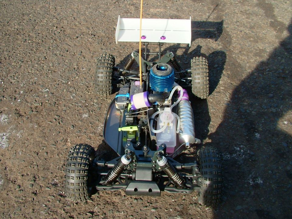Top-down view of a radio-controlled nitro buggy with a blue engine and white spoiler