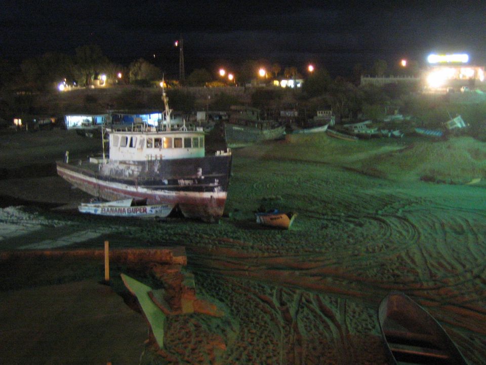 Boats beached on harbor flat at night, one marked Banana Super