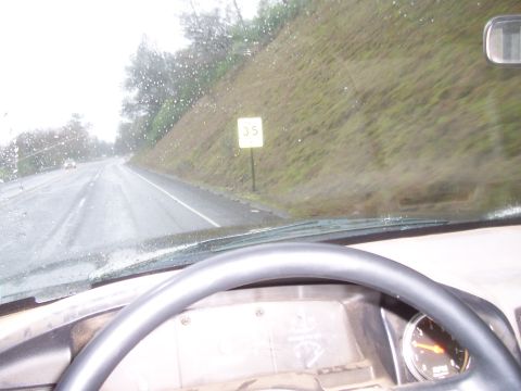 1994 Ford F-150 - View from inside a vehicle driving on a wet road, with a speed limit sign visible on the side of the road.
