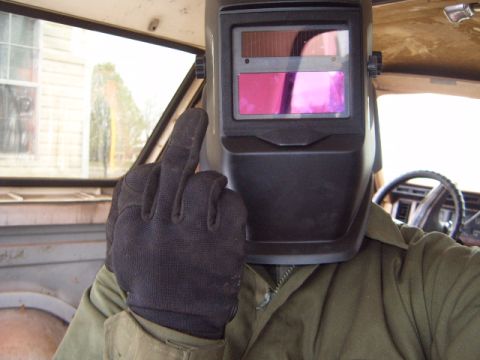 1988 Ford Bronco - Welder inside a vehicle gives the middle finger, obscuring face with mask.