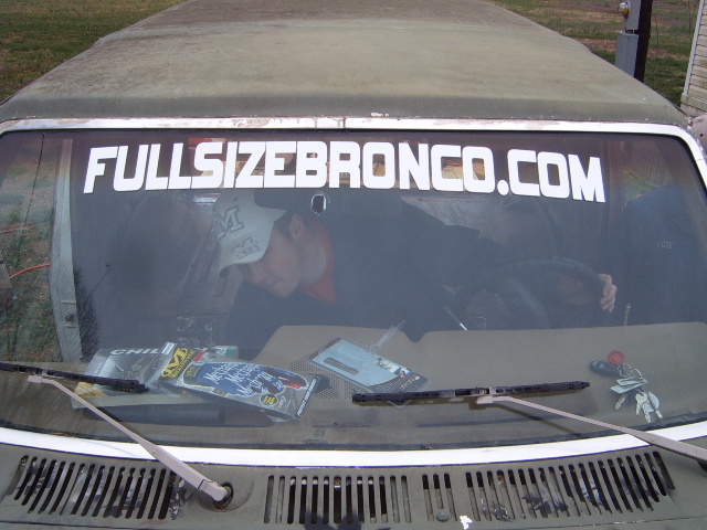Person wearing a cap inside a vehicle with a "FULLSIZEBRONCO.COM" sticker on the windshield