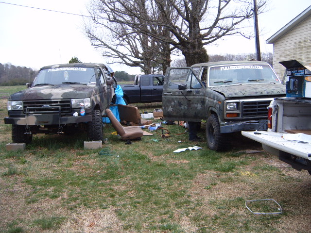 1980s Ford Bronco with open door, camouflage paint, parked outdoors