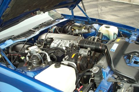 1990 Chevrolet Camaro - The engine bay of a 1990 Chevrolet Camaro, its V8 engine and blue exterior paint.