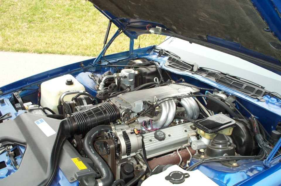 1990 Chevrolet Camaro engine bay with hood open, showing V8 engine and components