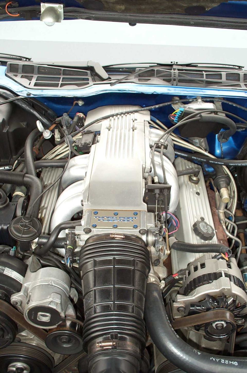 Close-up of a car's engine bay, showing the intake manifold and alternator