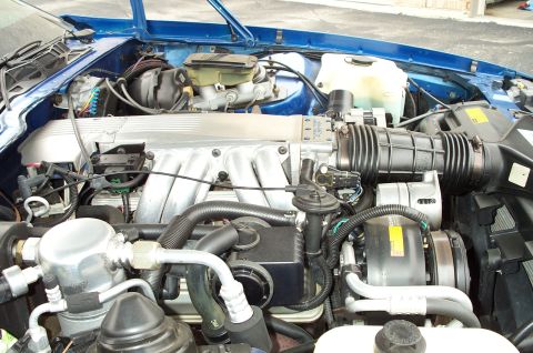 1990 Chevrolet Camaro - Close-up view of the engine bay of a blue Chevrolet Camaro, showing the V8 engine components.