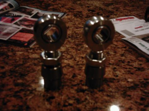 1978 Ford Bronco - A matched pair of large heavy-duty rod ends (Heim joints) standing on a granite countertop, each threaded into a black tube adapter with a…