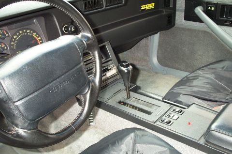 1990 Chevrolet Camaro - The interior of a 1990 Chevrolet Camaro shows the steering wheel, dashboard gauges, and automatic transmission shifter.