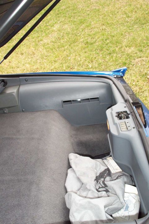 1990 Chevrolet Camaro - The trunk interior of a 1990 Chevrolet Camaro, gray carpet and plastic trim.