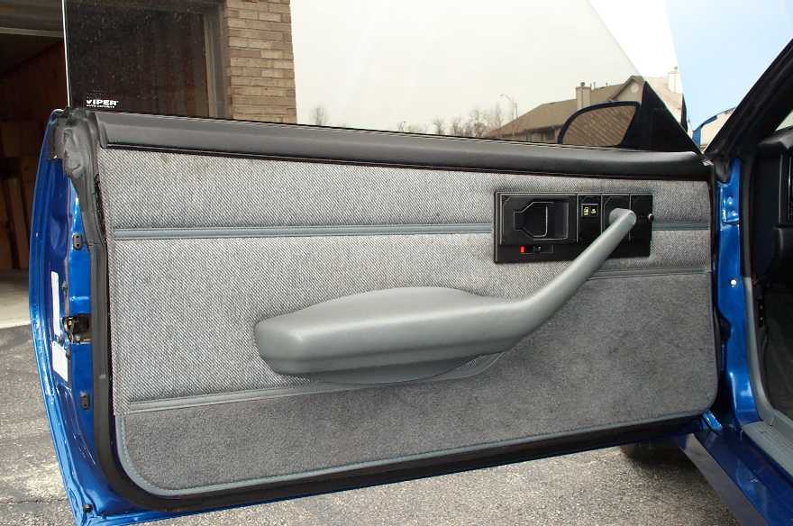 Interior of a blue car's door panel with gray fabric and a gray armrest