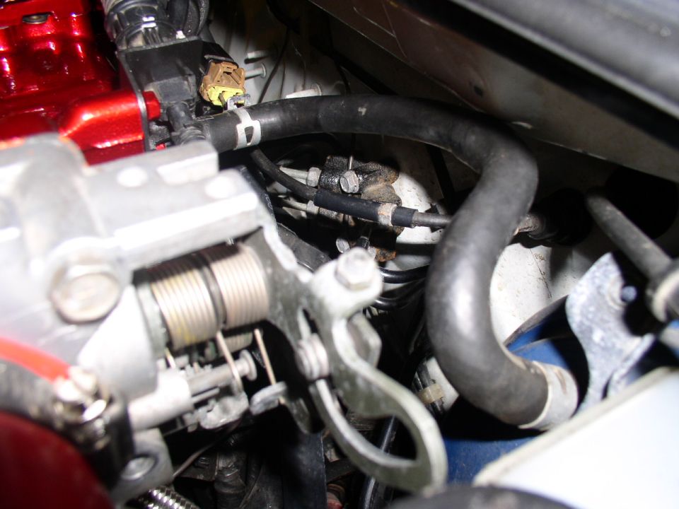Close-up of engine throttle body with springs and hoses. Supermotors.net logo visible