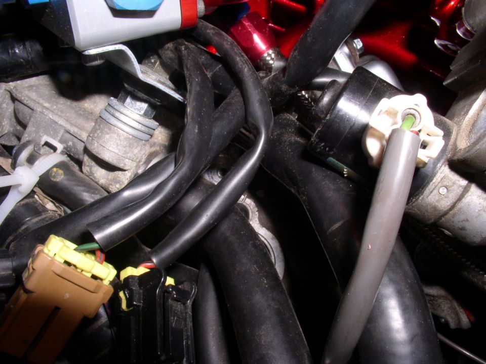 Engine wiring harness with yellow and brown connectors, black hoses, and a gray conduit