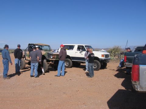 1990 Ford Bronco - Two Ford Broncos and a Ford truck are parked on a dirt lot under a clear blue sky.