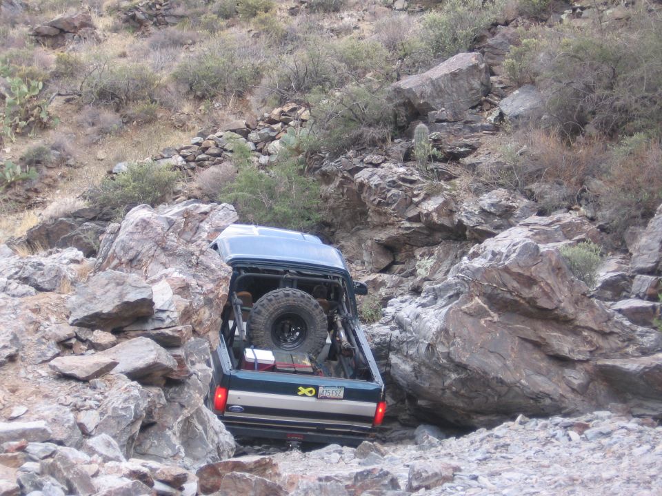 1990 Ford Bronco rear view navigating rocky terrain