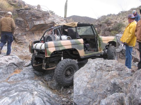 1990 Ford Bronco - This heavily modified Ford Bronco is tackling a challenging rocky trail in a desert environment.
