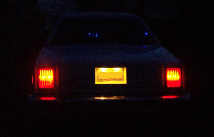 Rear of a sedan at night with lit tail lights and a yellow Virginia license plate