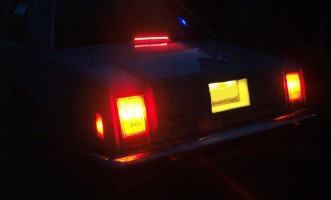 1985 Ford LTD Crown Victoria - The rear of a car is illuminated by its taillights and a lit license plate area at night.