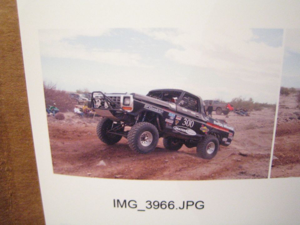 Photo of a black off-road race truck number 300 with tube bumper parked in the desert