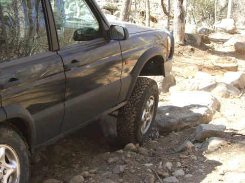 1996 Ford Bronco - A dark-colored SUV is shown traversing a challenging rocky path, highlighting its off-road capabilities.