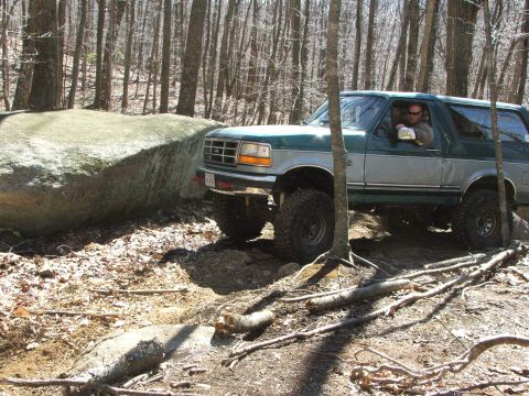 1996 Ford Bronco - A 1996 Ford Bronco navigates a rocky trail in a forest setting.