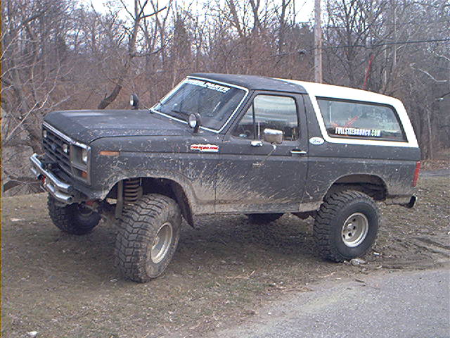 Muddy 1980 Ford Bronco with lifted suspension and off-road tires parked on dirt