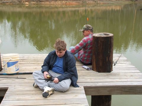 1966 Ford Ranchero - Two individuals enjoy a day of fishing from a wooden dock, with one person actively holding a fishing rod.