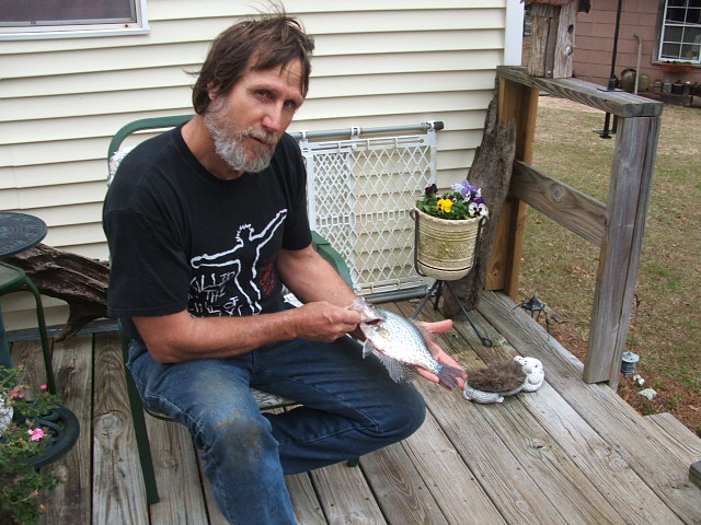 Man on a porch holding a crappie fish