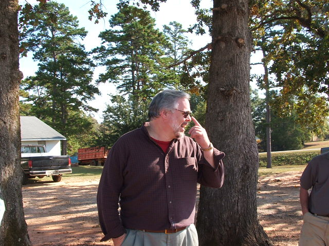 Man looking up and to the side, with a pickup truck and trailer in the background