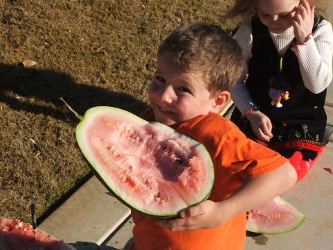1966 Ford Ranchero - A boy smiles while holding a large slice of watermelon, with a girl visible behind him.
