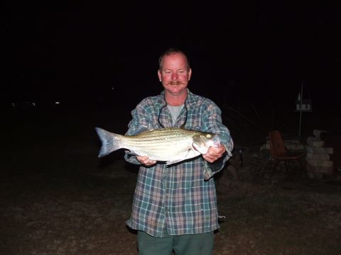 1966 Ford Ranchero - Man proudly displays a large striped fish caught at night, with a Supermotors.net logo in the corner.