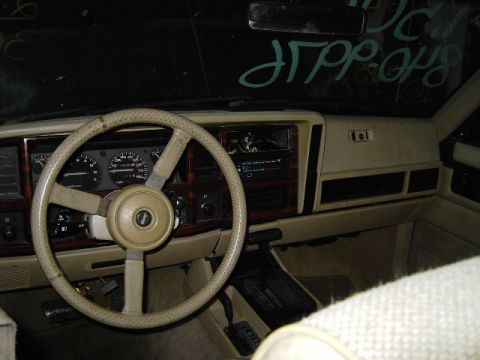 1993 Jeep Cherokee - The interior of a 1993 Jeep Cherokee shows a beige dashboard with wood accents and a Jeep logo on the steering wheel.