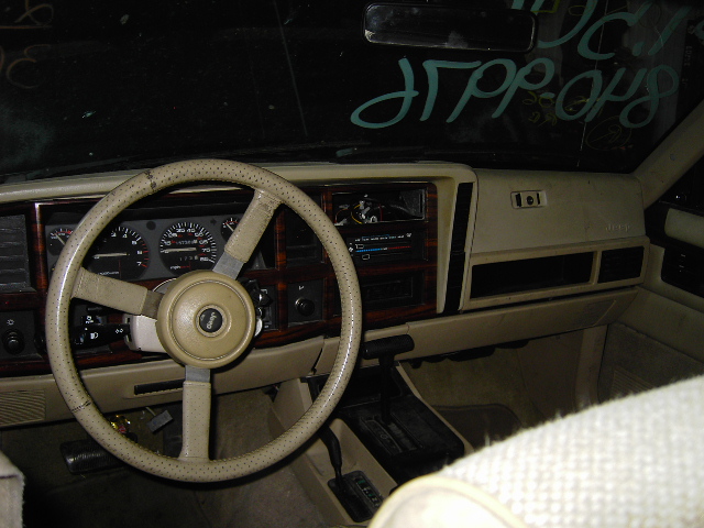 1993 Jeep Cherokee interior with beige dashboard, wood trim, and a Jeep-branded steering wheel