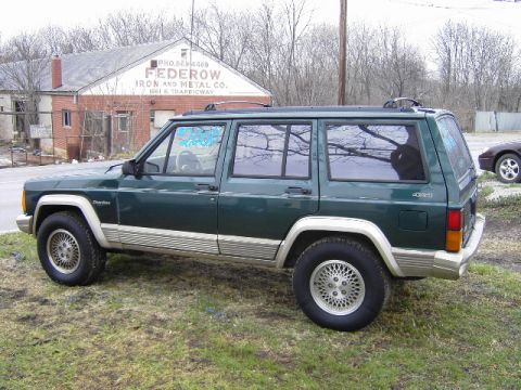 1993 Jeep Cherokee - A green Jeep Cherokee is parked on a grassy area next to a brick building with "FEDEROW IRON AND METAL CO." painted on it.