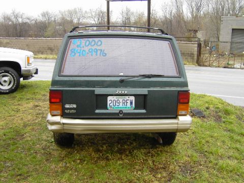 1993 Jeep Cherokee - The rear of a green 1993 Jeep Cherokee is visible, parked next to a white pickup truck.