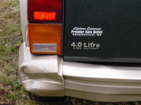 1993 Jeep Cherokee - A dented rear bumper and taillight are visible on a 1993 Jeep Cherokee, along with a '4.0 Litre HIGH OUTPUT' badge.